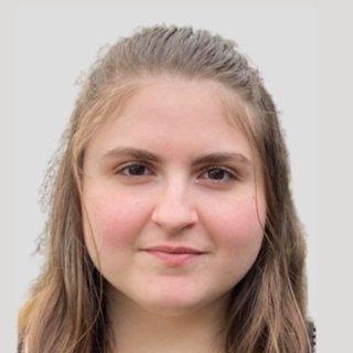 Portrait of a young woman with long brown hair facing the camera with a neutral expression against a light background.